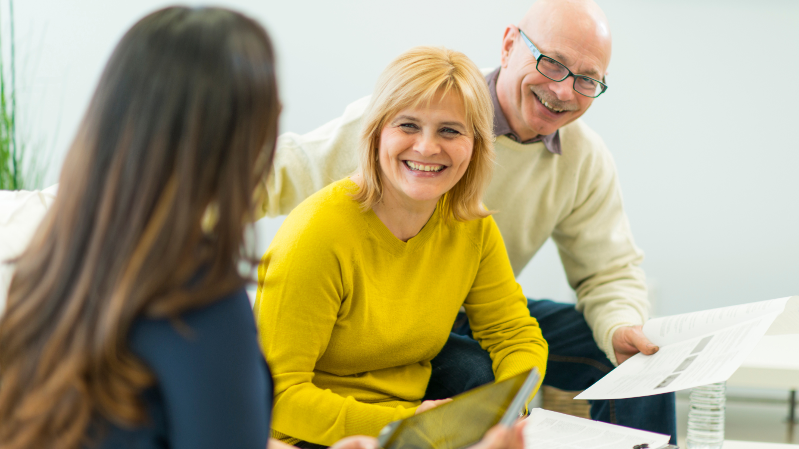 Older couple smiling holding sheets of paper.