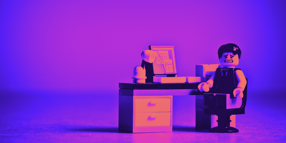 Lego figure of a man at a computer desk.