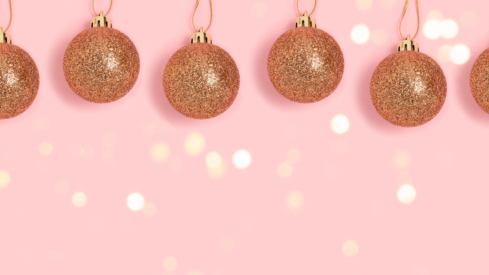 Gold baubles against a pink background.