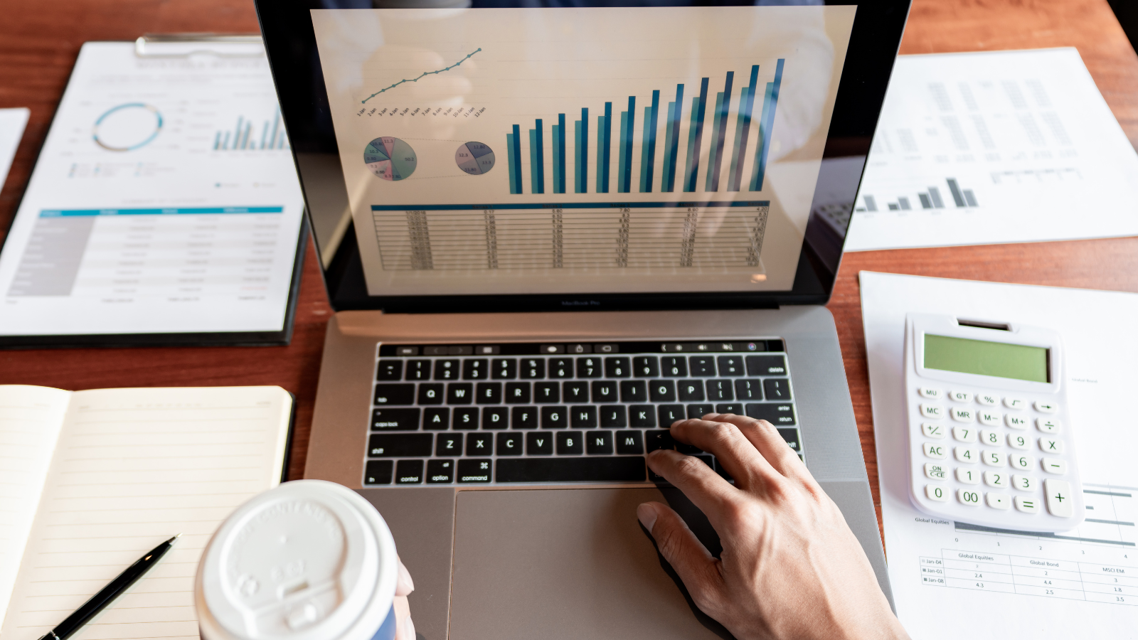 Laptop showing a chart. A calculator is placed next to the laptop. 