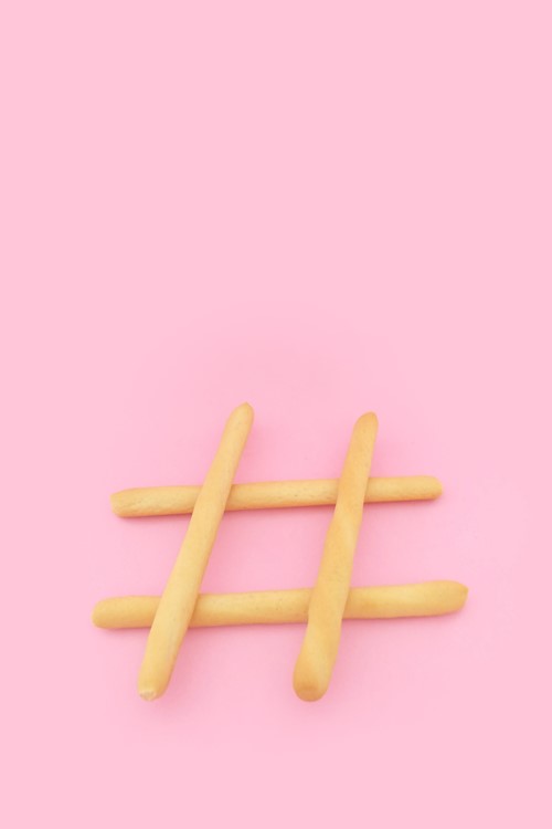 Hashtag made from french fries stacked on top of each other against a baby pink background.