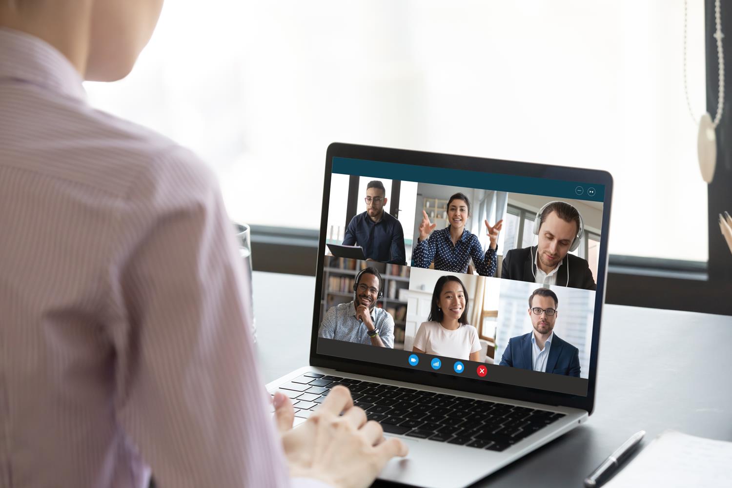 A laptop showing faces on a virtual meeting.