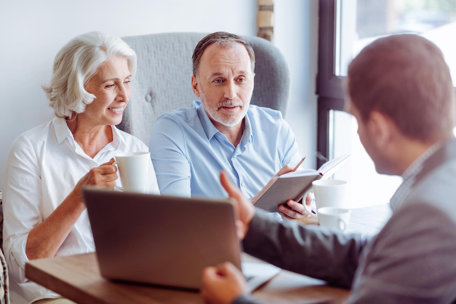 A financial advisor showing a couple something on his laptop.