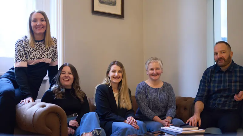 Team photo: Everyone is sitting on a brown leather sofa. Pictured left to right: Rachel Wright, Marianne Carey, Erin Cassidy, Alison O'Neill and Chris Lucarelli.