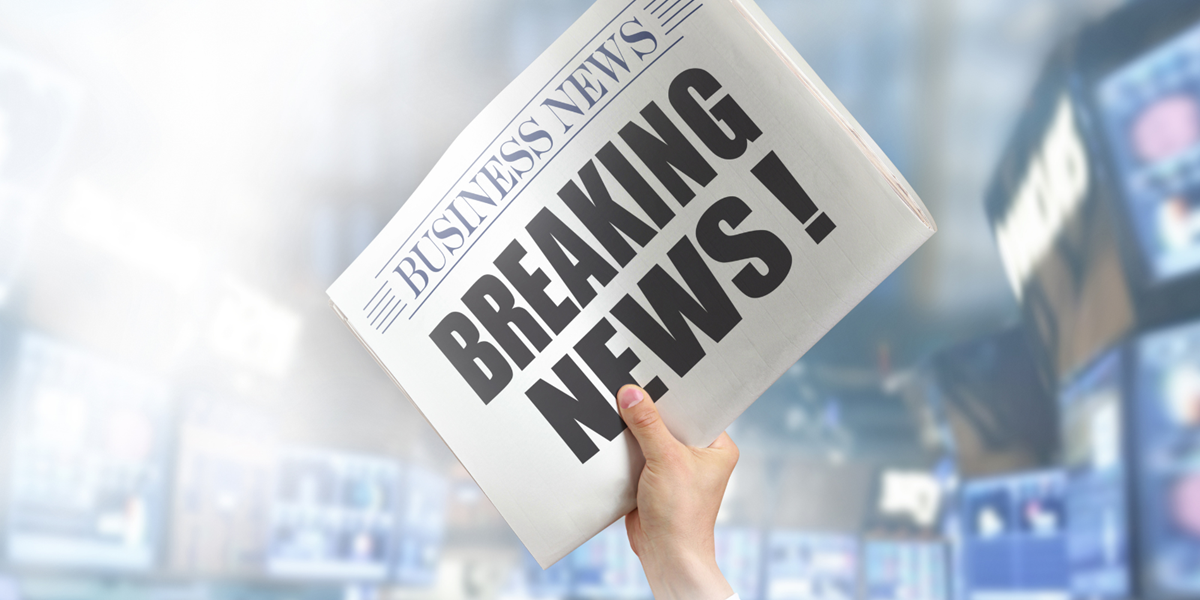 Hand holding newspaper with 'breaking news' written on. 