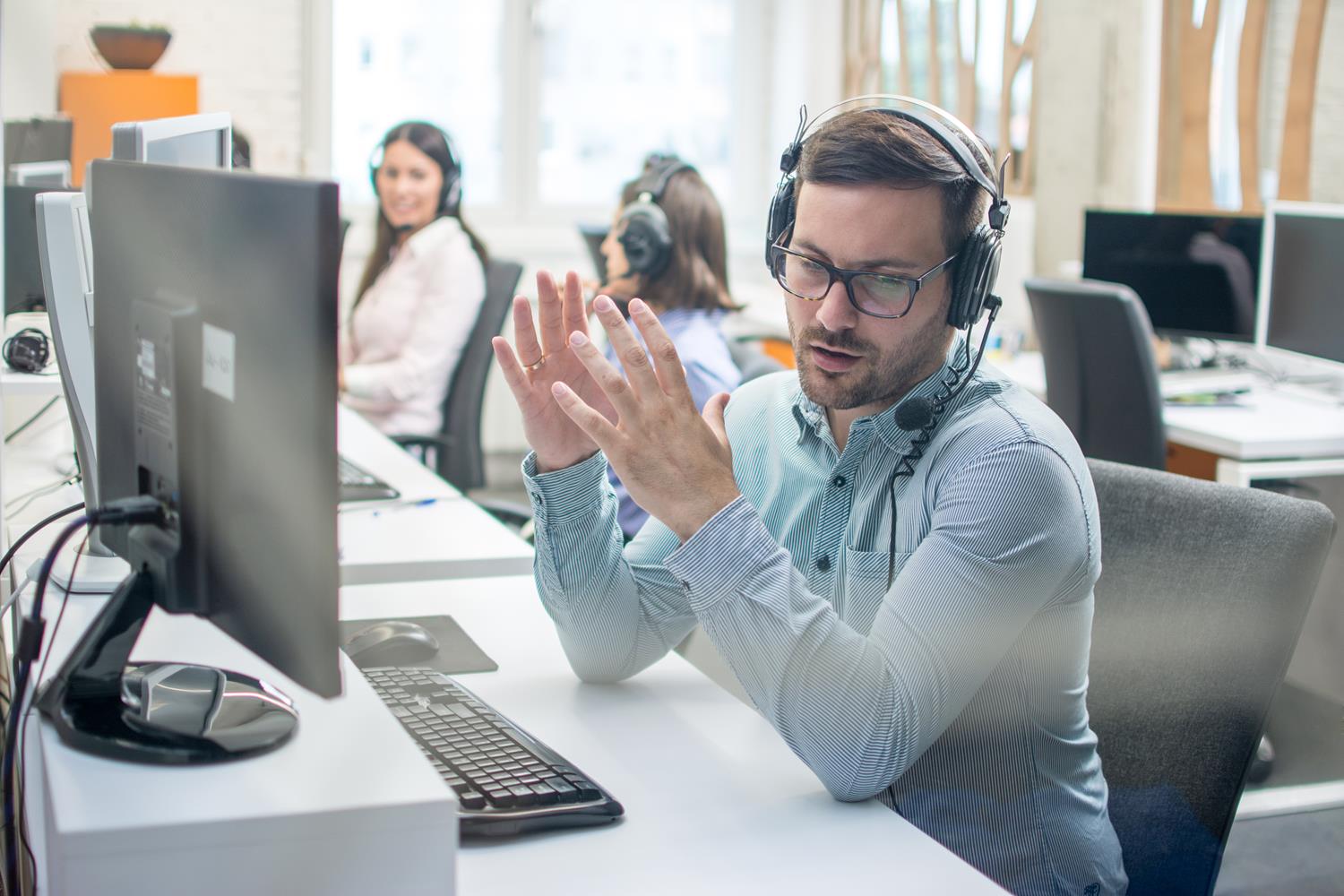 Claims management: Man sits talking to a customer through a headset.