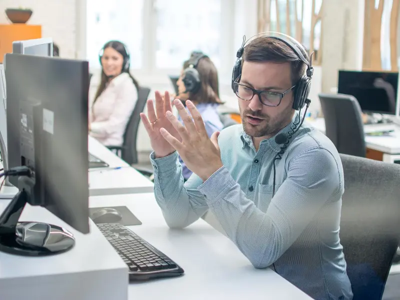 Claims management: Man sits talking to a customer through a headset.