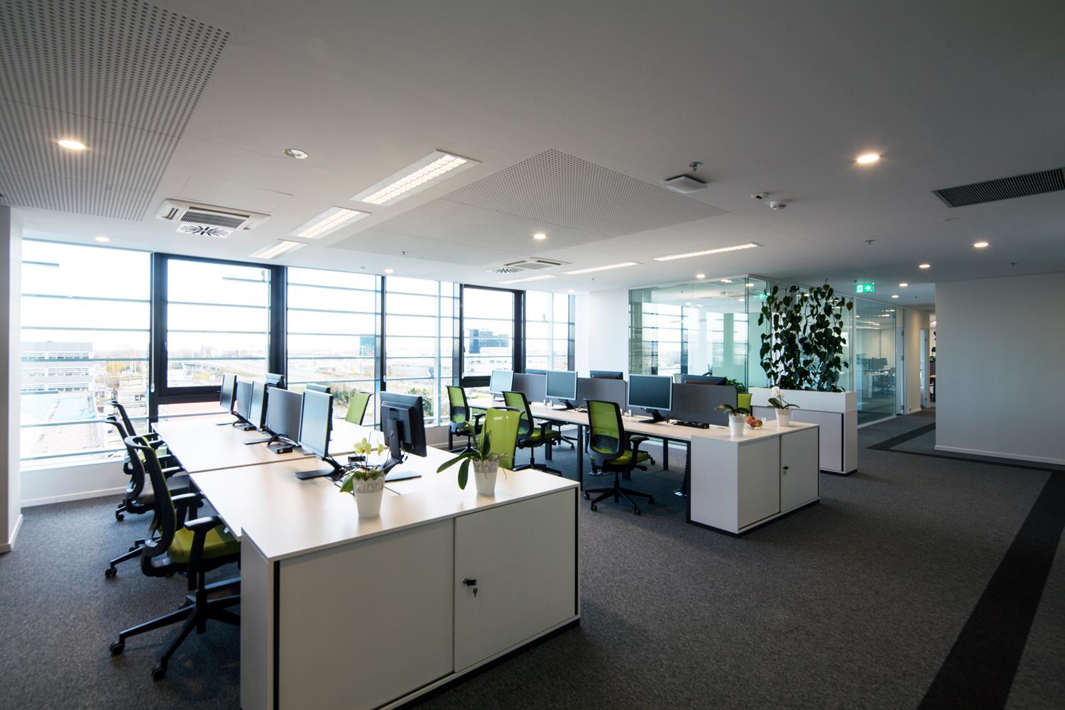 Office interior showing a bank of desks with computers and chairs.