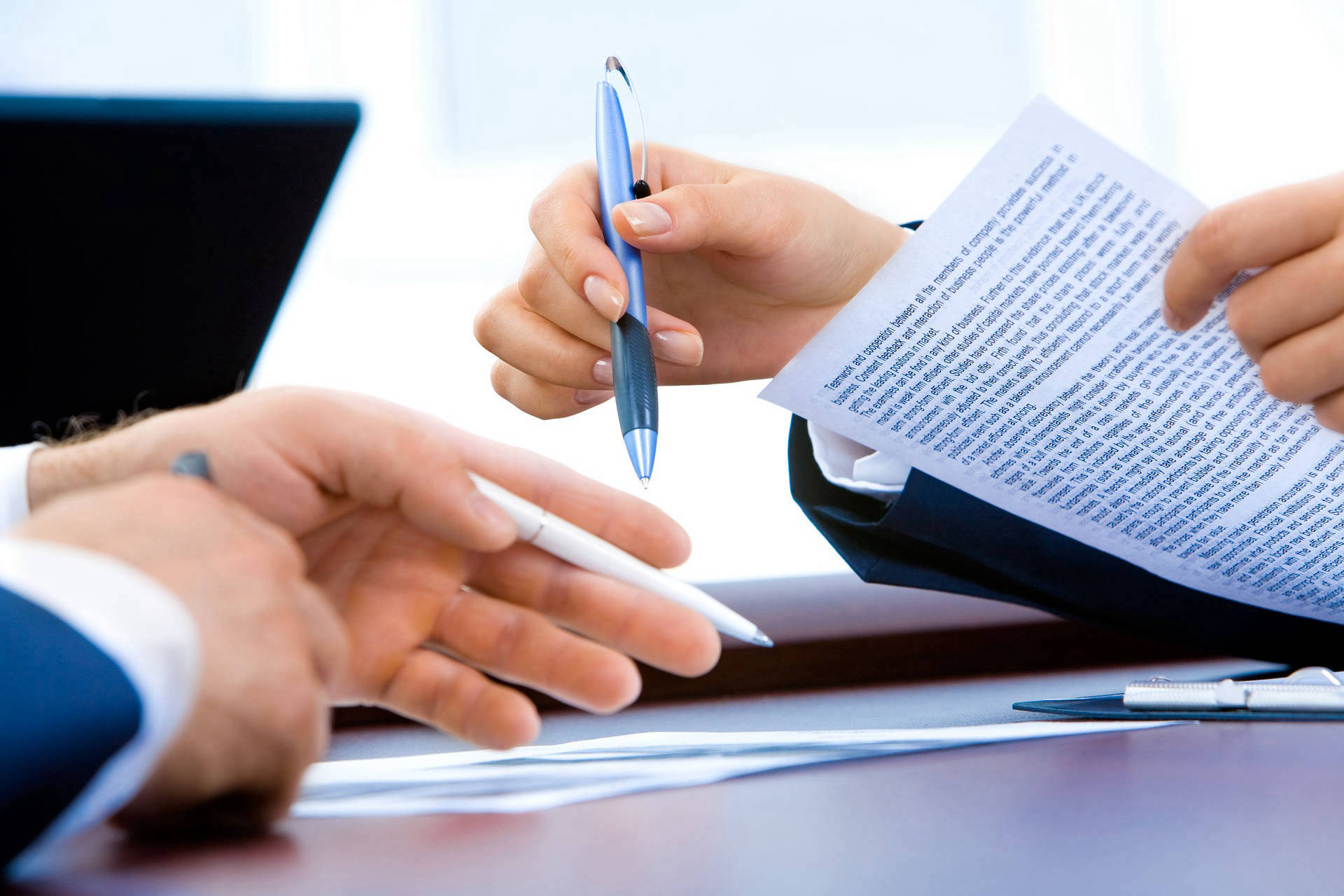 Two people pointing at documents with their pens.